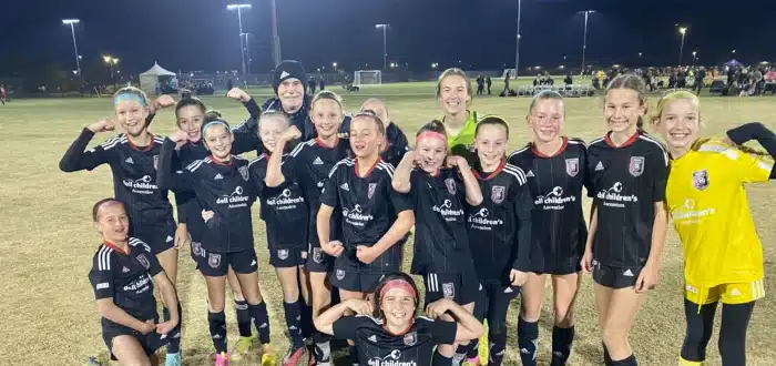 Youth soccer team celebrating victory on the field at night with smiles and poses