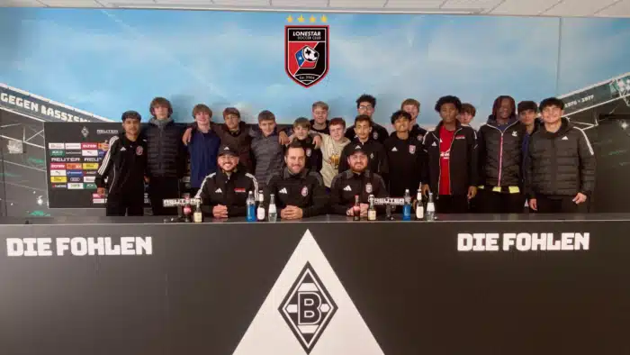 Soccer team group photo with coaches at a press conference table