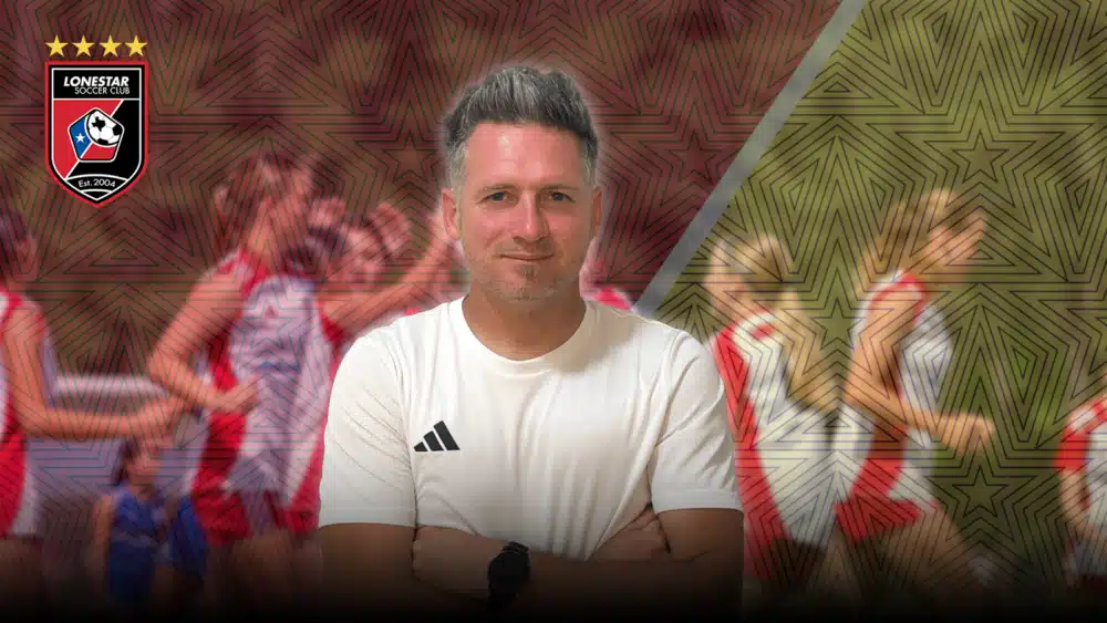 Soccer coach in white shirt with team logo background and blurred players in motion