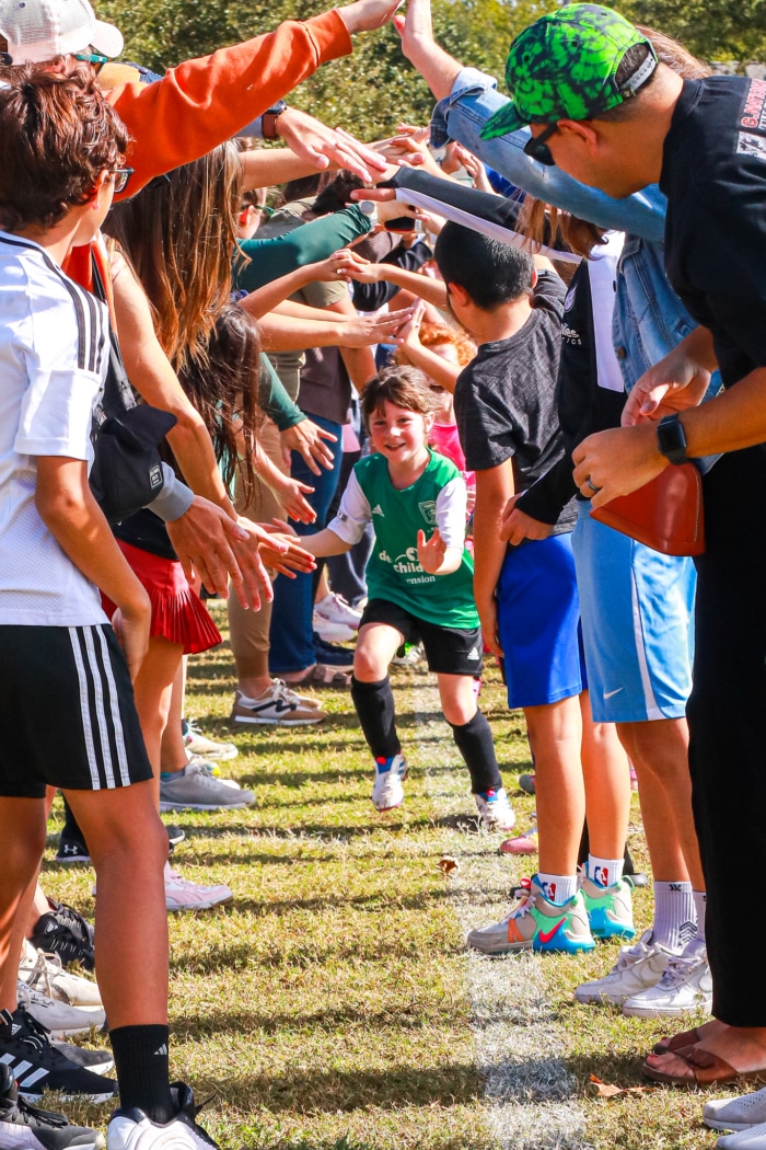 Child running through cheering crowd on sports field