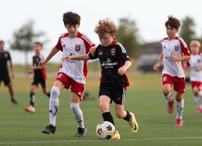 Youth soccer players competing on a field during a sunny day
