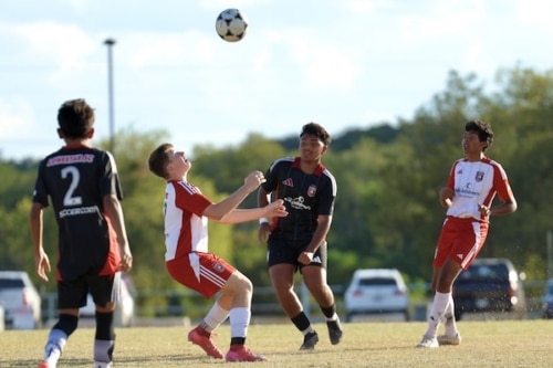 Youth soccer players in action under a clear sky on a grassy field