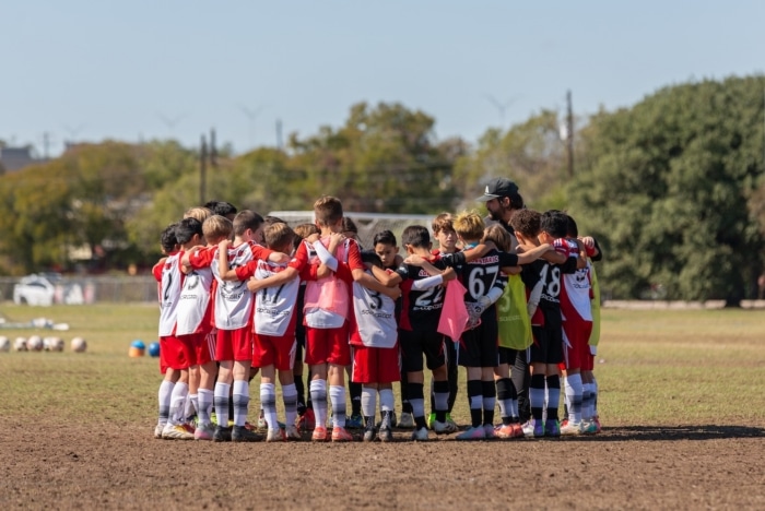 Youth soccer team huddle on a sunny field for pre-game motivation and strategy discussion